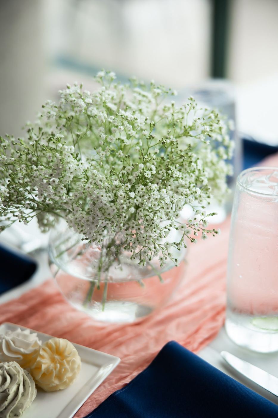 Baby's breath in a round glass vase on a blush runner