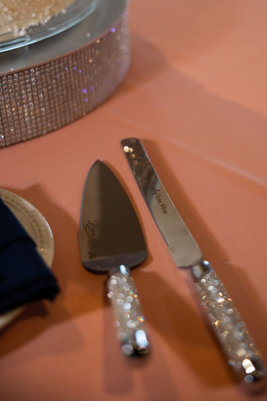 Crystal-handled cake knife and server on a blush tablecloth