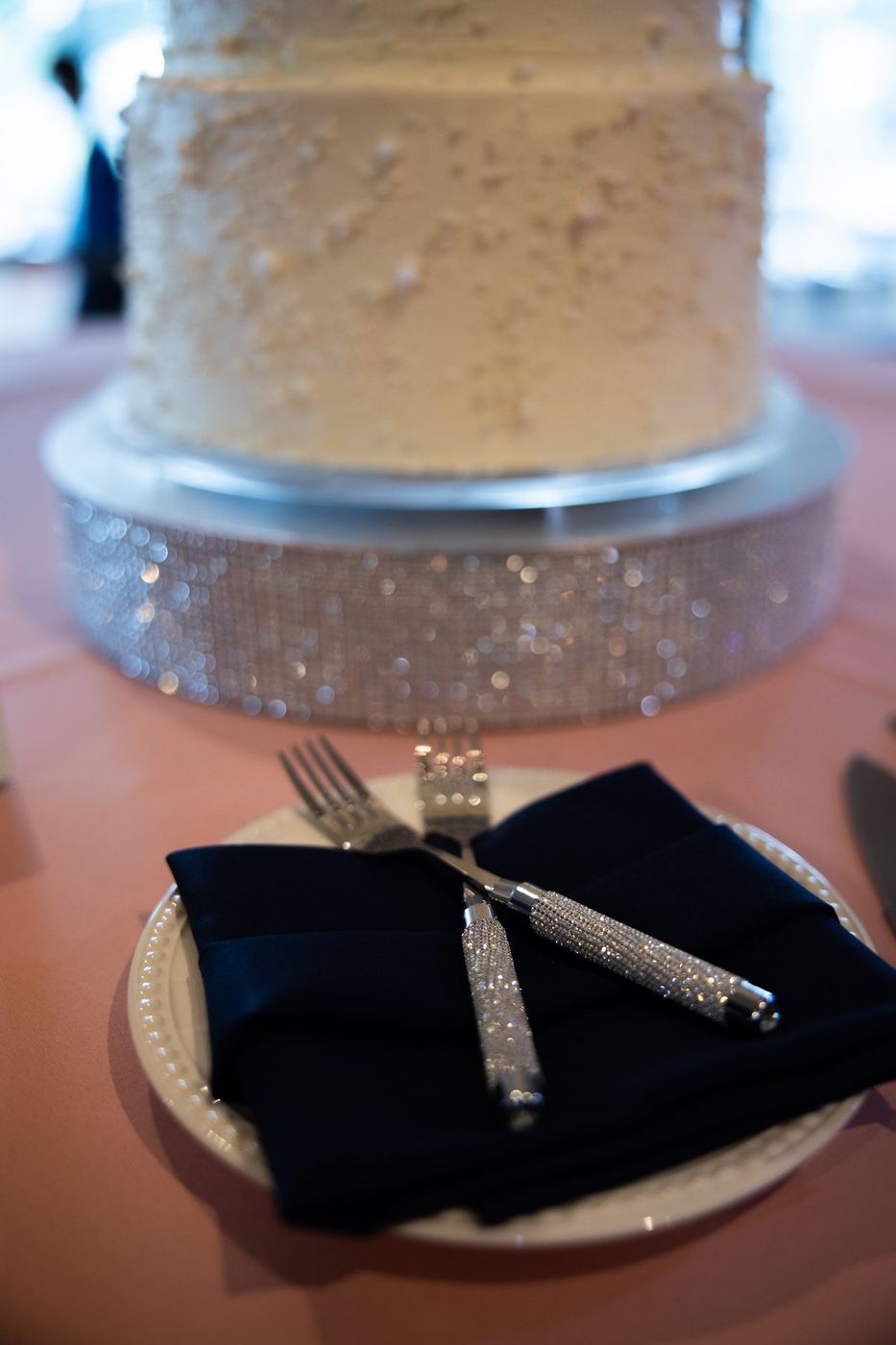 Navy napkin and crystal cake forks in front of the wedding cake