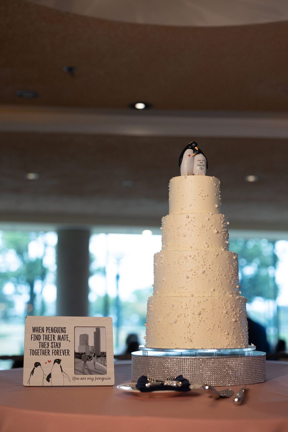 Four-tier white wedding cake with penguin topper